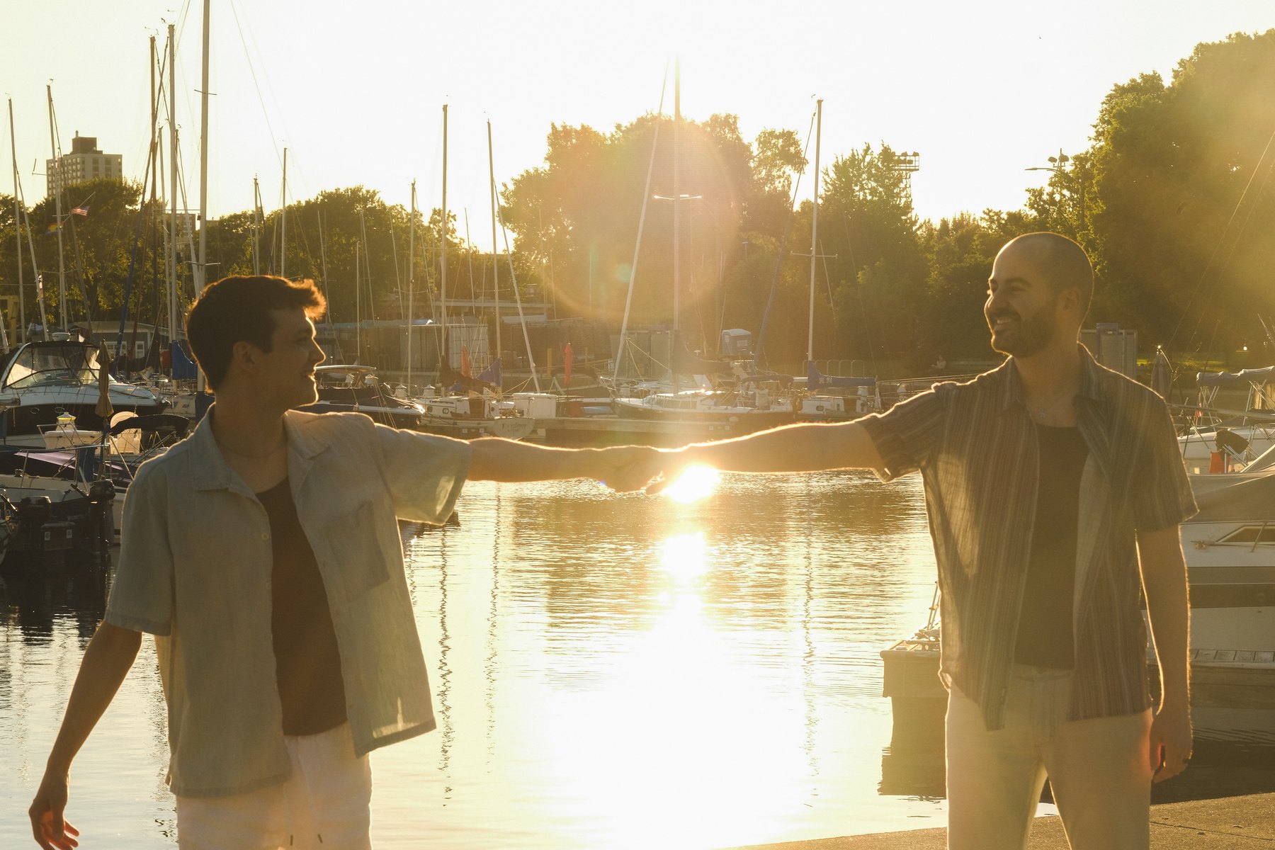 Jacob and Bradley holding hands at the marina at sunset