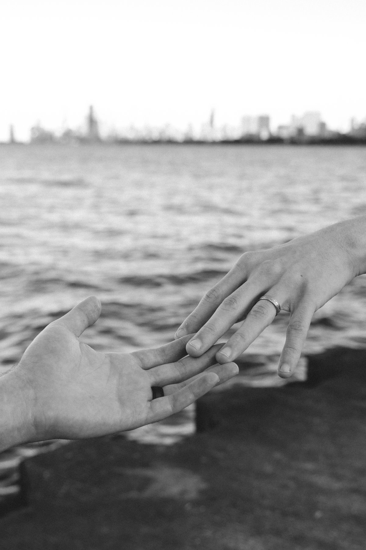 Jacob and Bradley reaching for each other’s hands with an engagement ring visible