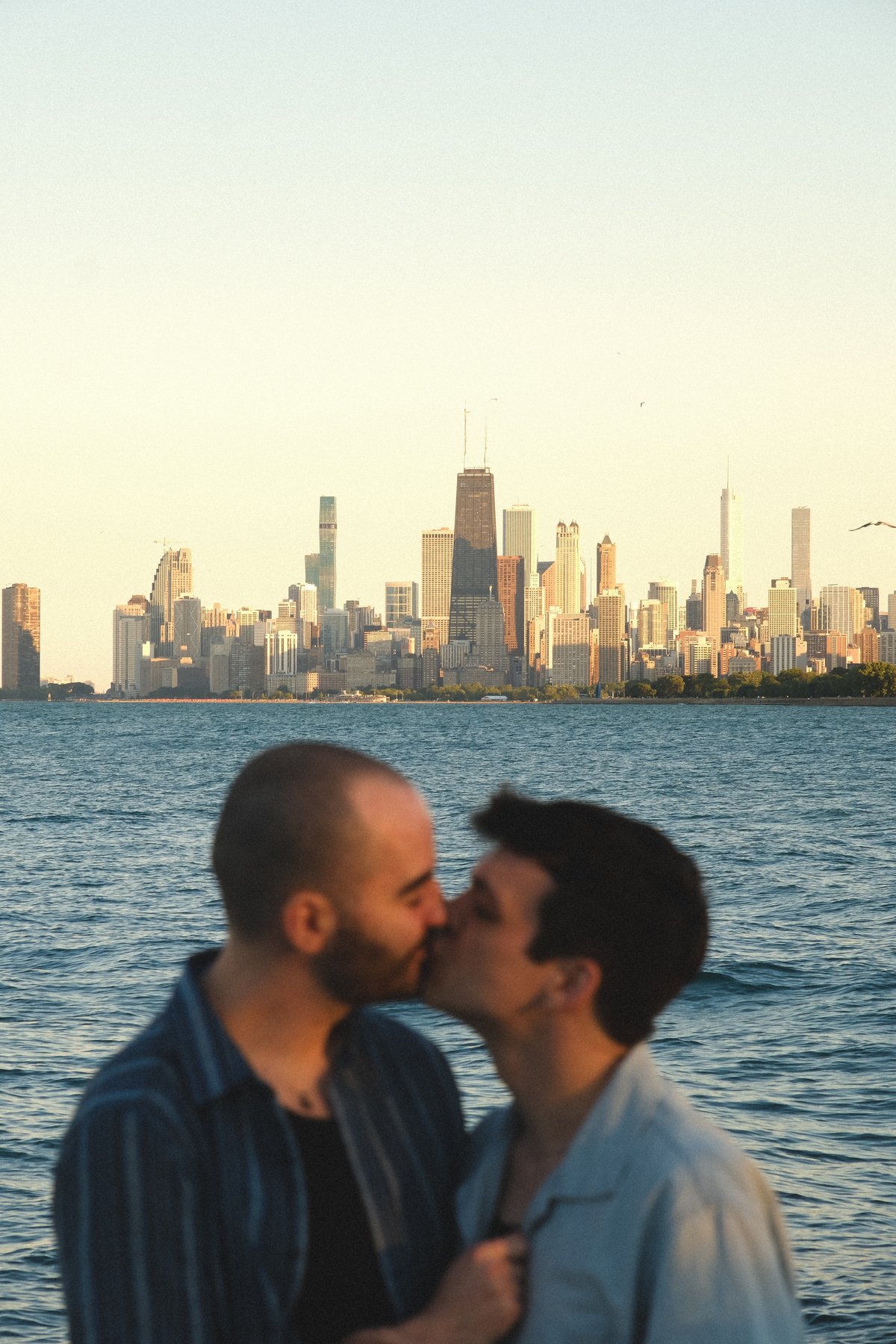 Jacob and Bradley kissing with the Chicago skyline behind them