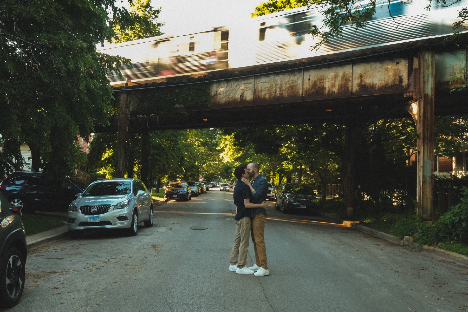 Jacob and Bradley kissing beneath the elevated train as a train passes overhead